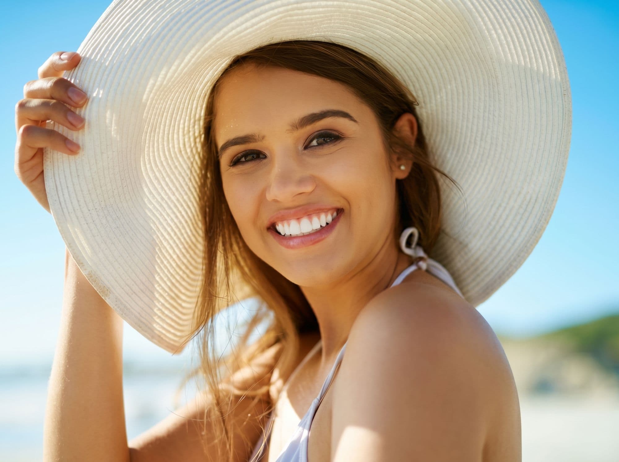 Smiling woman in a sun hat, representing cosmetic bonding at East River Dental